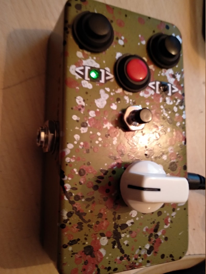 May include: A green and black speckled guitar effects pedal with three knobs, two buttons, a toggle switch, and a white knob. The pedal has a green LED light that is on.