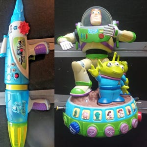 May include: Two Toy Story themed toys. One is a blue and white water gun with a red dial and the word "Buzz" on it. The other is a Buzz Lightyear figure standing on a platform with an alien figure.