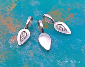 May include: Three silver-toned metal pendant bails with a teardrop shape. The bails have a textured surface and a loop at the top for attaching a pendant.