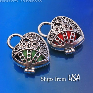 May include: Two silver heart-shaped locket charms with intricate floral designs. One locket has a red fan-shaped interior, and the other has a green fan-shaped interior.