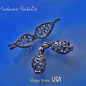 May include: Three silver filigree charm pendants in the shape of teardrops. The pendants are openwork and have a delicate design.