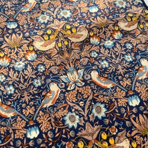 May include: A navy blue fabric with a repeating pattern of birds, flowers, and foliage in shades of brown, beige, and blue. The design features detailed illustrations of birds perched among stylized floral elements. The overall aesthetic is reminiscent of vintage textile designs.