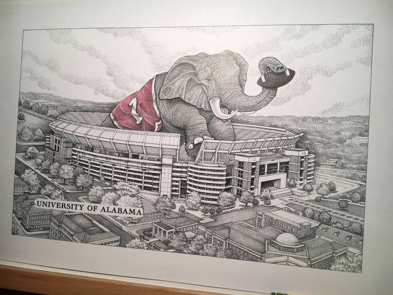 May include: A black and white illustration of an elephant wearing a red and white jersey with the number "1" on it. The elephant is holding a football and is standing in front of a stadium. The text "UNIVERSITY OF ALABAMA" is visible at the bottom of the image.