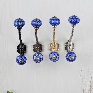 May include: Four decorative wall hooks with blue and white ceramic knobs. The hooks are made of metal and have a twisted design. The hooks are available in black, bronze, gold, and silver finishes.