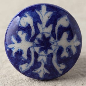 May include: A blue and white ceramic knob with a floral design. The knob is round and has a glossy finish.