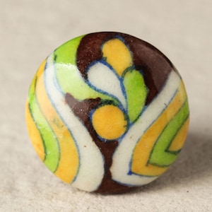 May include: A round ceramic knob with a colourful abstract design. The knob features swirls of yellow, green, brown, and white.