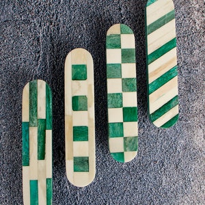 Puede incluir: Cuatro tiradores decorativos para cajones hechos de hueso e incrustaciones verdes. Cada tirador presenta un patrón geométrico diferente.