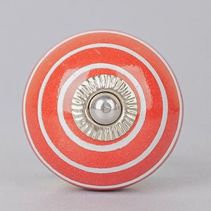 Puede incluir: Un pomo de cerámica rayado en rojo y blanco con una base de metal plateado.