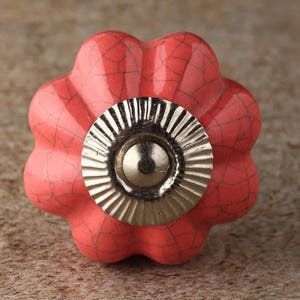 Op de afbeelding: Een roze keramische kastknop met een gekrakelde afwerking en een zilveren metalen kern.