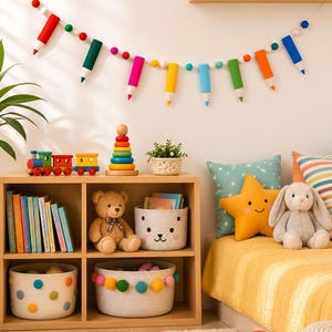 May include: A colorful felt garland featuring pencil-shaped ornaments and small spheres in red, green, pink, yellow, blue, and orange, strung on a white cord and displayed against a wall above a wooden shelving unit filled with toys and books.