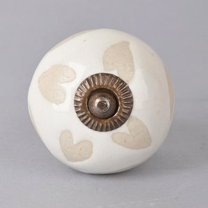 May include: White ceramic knob with a brown heart pattern and a gold metal center.