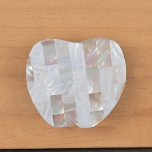 Op de afbeelding: Een witte, hartvormige ladegreep gemaakt van parelmoer tegels.