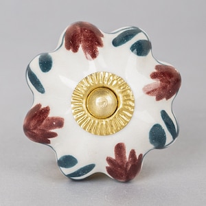May include: White ceramic knob with a gold center and a floral design in shades of brown and teal.