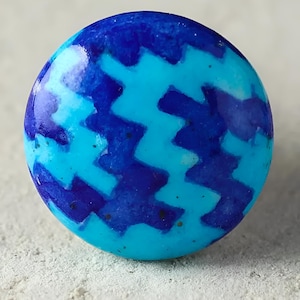 Puede incluir: Un pomo redondo de cerámica azul y blanco con un patrón de zigzag.