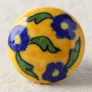 May include: A yellow ceramic knob with a blue and green floral design. The knob has a smooth, rounded surface and is perfect for adding a touch of traditional style to any room.