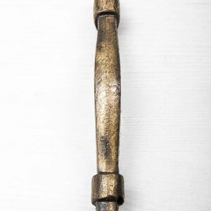 Puede incluir: Una manija de puerta de metal dorado con un diseño simple y elegante. La manija tiene una forma redondeada y un acabado ligeramente texturizado.