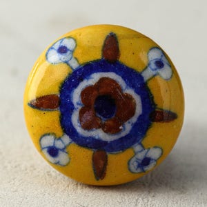 May include: A yellow ceramic knob with a blue and brown floral design. The knob has a glossy finish and is perfect for adding a touch of traditional style to any room.