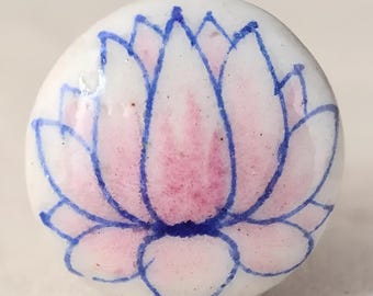 May include: A white ceramic knob with a pink and blue lotus flower design.