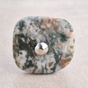 May include: A square-shaped green, white, and brown agate stone with a silver metal accent. The stone has a mottled pattern.