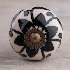 Peut inclure: Bouton de porte en céramique blanche avec un motif floral noir et un accent en laiton.