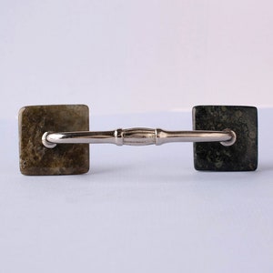 May include: A silver cabinet pull with square, green and brown stone accents.