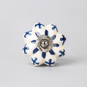 May include: White ceramic knob with a blue floral pattern and a silver center.