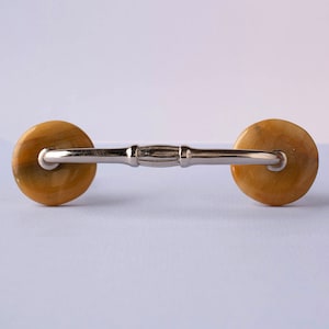 May include: A silver cabinet knob with two round, brown, and gold-toned ceramic handles.
