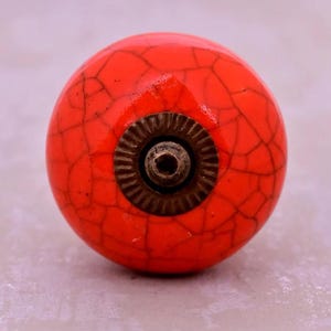 Può includere: Un pomello per armadietto rotondo in ceramica arancione con effetto craquelé. Il pomello presenta una base e una vite in metallo color bronzo scuro. Questo hardware decorativo è adatto per cassetti, armadi e mobili.