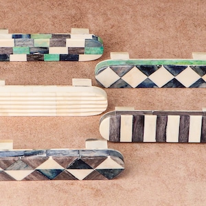 Puede incluir: Cinco tiradores decorativos para cajones hechos de hueso e incrustados con patrones geométricos coloridos. Los tiradores son de forma ovalada y tienen un acabado pulido.