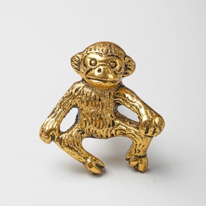 May include: A gold-colored monkey figurine with a sitting pose. The monkey has a detailed textured surface and a realistic expression.