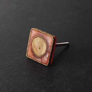 Può includere: Pomo quadrato per armadio con un design a venature del legno al centro, circondato da un bordo rosso e dorato.