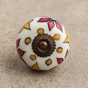 Könnte beinhalten: Weißer Keramik-Schrankknopf mit floralem Design in Rot, Gelb und Blau. Der Knopf hat einen bronzefarbenen Sockel und eine runde Form. Diese dekorative Hardware verleiht jedem Möbelstück einen Farbtupfer.