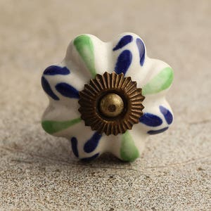 May include: White ceramic knob with a blue and green floral design and a brass screw.