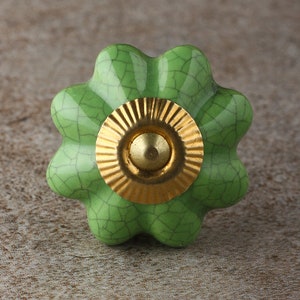 May include: A green ceramic knob with a gold center. The knob has a crackled finish and a flower-like shape.