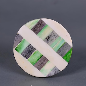 Puede incluir: Posavasos redondo con fondo blanco y un patrón geométrico de rayas verdes, negras y blancas.