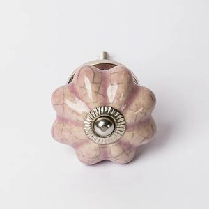 May include: A pink ceramic cabinet knob with a crackled glaze finish and a silver metal base.
