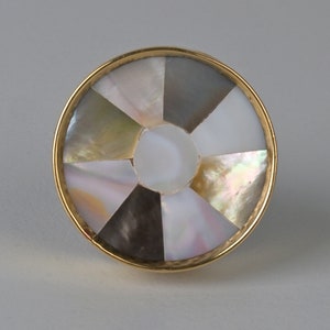 May include: A round, gold-toned knob with a circular design of iridescent mother-of-pearl pieces.