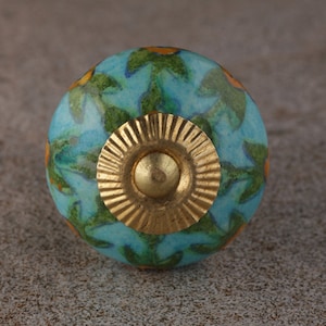 May include: A blue ceramic knob with a gold metal base and a floral pattern. The knob has a green and orange floral design.