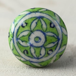 May include: A green ceramic knob with a white and blue floral design. The knob has a circular shape and is perfect for adding a touch of traditional style to any home.