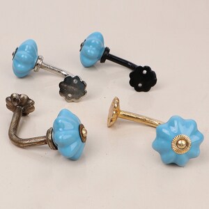 May include: Four ceramic hooks with a blue and white floral design. The hooks are in different finishes: silver, black, gold, and bronze.