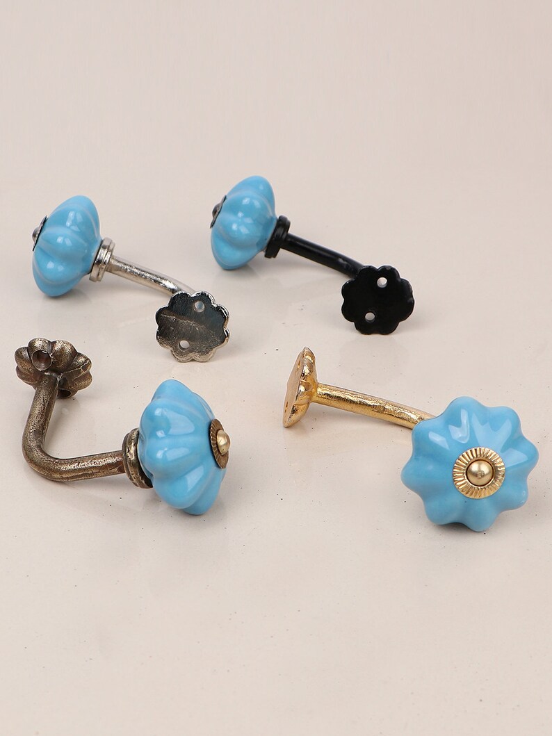 May include: Four ceramic hooks with a blue and white floral design. The hooks are in different finishes: silver, black, gold, and bronze.