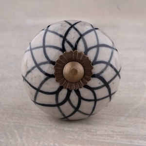 May include: White ceramic knob with a black swirl pattern and a gold metal center.