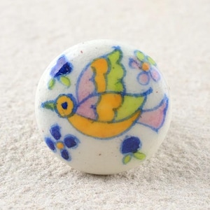 May include: White ceramic knob with a hand-painted design of a yellow, pink and green bird with blue flowers.