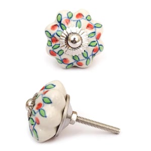 May include: Two ceramic cabinet knobs with a floral design. The knobs are white with red and green floral accents and a silver-colored metal base. The knobs are approximately 2 inches in diameter.
