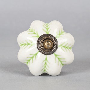 May include: White ceramic cabinet knob with a green floral design and a brass center.
