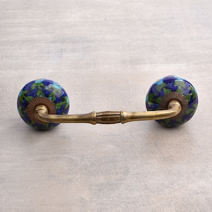 May include: A brass drawer pull with two blue and green ceramic knobs. The knobs have a floral pattern.