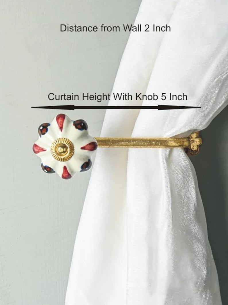 May include: Gold curtain rod with a white ceramic knob with red and blue accents. The knob is 5 inches tall and the rod extends 2 inches from the wall.