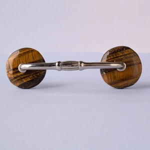 May include: A silver cabinet pull with two round tiger's eye knobs.