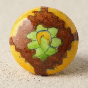 May include: A yellow ceramic knob with a brown and green floral design. The knob is round and has a glossy finish.
