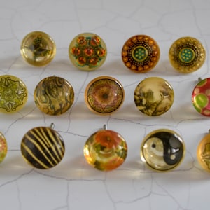 Peut inclure: Assortiment de 13 boutons de cabinet décoratifs avec différents motifs. Les boutons sont ronds et présentent une variété de motifs, notamment des motifs floraux, géométriques et abstraits. Les boutons sont en verre et ont une finition transparente et translucide.